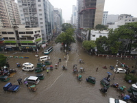 People are going through a flooded street after heavy monsoon rainfall in Dhaka, Bangladesh, on July 12, 2024. (