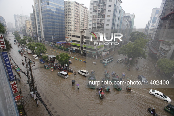 People are going through a flooded street after heavy monsoon rainfall in Dhaka, Bangladesh, on July 12, 2024. 