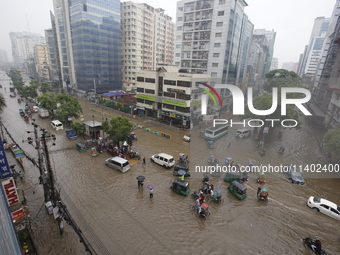 People are going through a flooded street after heavy monsoon rainfall in Dhaka, Bangladesh, on July 12, 2024. (