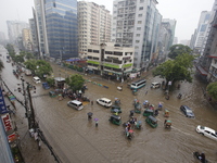 People are going through a flooded street after heavy monsoon rainfall in Dhaka, Bangladesh, on July 12, 2024. (