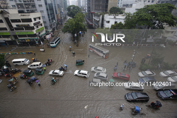 People are going through a flooded street after heavy monsoon rainfall in Dhaka, Bangladesh, on July 12, 2024. 