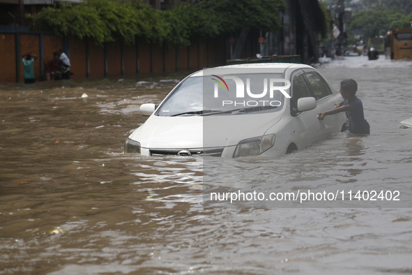 A boy is pulling a vehicle through a flooded street after heavy monsoon rainfall in Dhaka, Bangladesh, on July 12, 2024. 