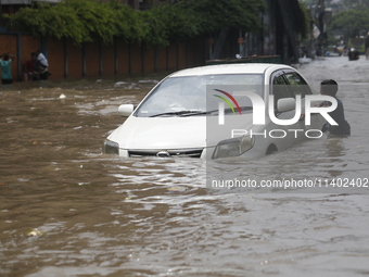 A boy is pulling a vehicle through a flooded street after heavy monsoon rainfall in Dhaka, Bangladesh, on July 12, 2024. (