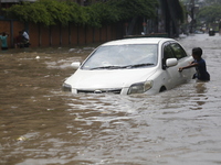 A boy is pulling a vehicle through a flooded street after heavy monsoon rainfall in Dhaka, Bangladesh, on July 12, 2024. (