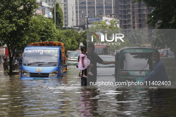 People are going through a flooded street after heavy monsoon rainfall in Dhaka, Bangladesh, on July 12, 2024. 