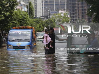 People are going through a flooded street after heavy monsoon rainfall in Dhaka, Bangladesh, on July 12, 2024. (