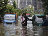 People are going through a flooded street after heavy monsoon rainfall in Dhaka, Bangladesh, on July 12, 2024. (