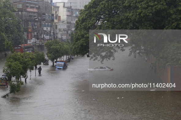 People are going through a flooded street after heavy monsoon rainfall in Dhaka, Bangladesh, on July 12, 2024. 