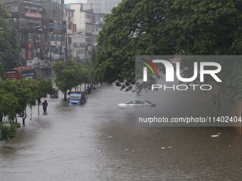 People are going through a flooded street after heavy monsoon rainfall in Dhaka, Bangladesh, on July 12, 2024. (