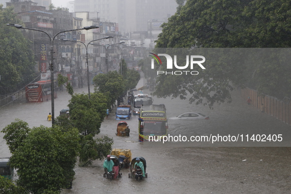 People are going through a flooded street after heavy monsoon rainfall in Dhaka, Bangladesh, on July 12, 2024. 