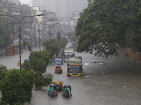 People are going through a flooded street after heavy monsoon rainfall in Dhaka, Bangladesh, on July 12, 2024. (