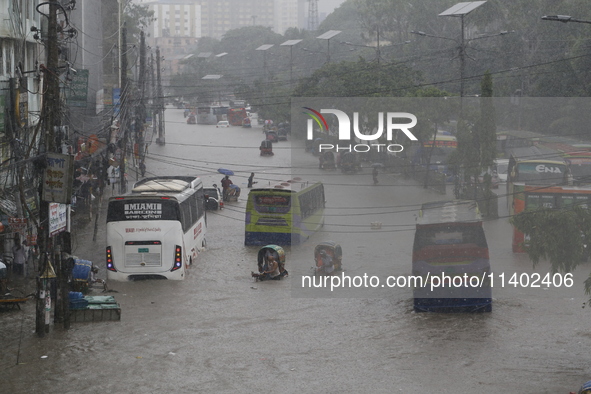 People are going through a flooded street after heavy monsoon rainfall in Dhaka, Bangladesh, on July 12, 2024. 