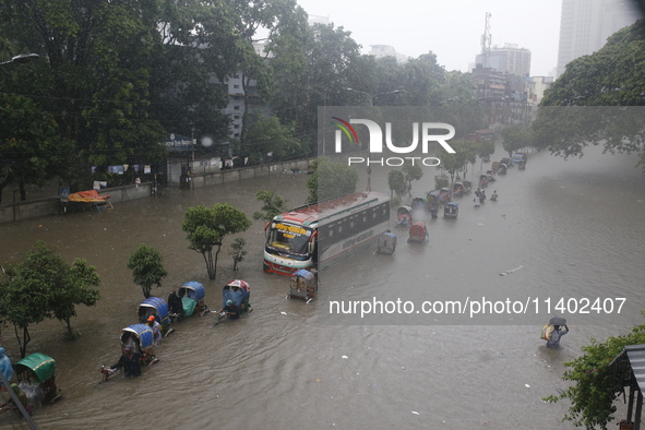 People are going through a flooded street after heavy monsoon rainfall in Dhaka, Bangladesh, on July 12, 2024. 