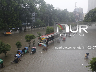 People are going through a flooded street after heavy monsoon rainfall in Dhaka, Bangladesh, on July 12, 2024. (