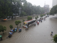 People are going through a flooded street after heavy monsoon rainfall in Dhaka, Bangladesh, on July 12, 2024. (