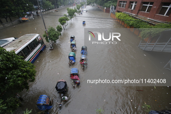 People are going through a flooded street after heavy monsoon rainfall in Dhaka, Bangladesh, on July 12, 2024. 