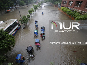 People are going through a flooded street after heavy monsoon rainfall in Dhaka, Bangladesh, on July 12, 2024. (