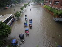 People are going through a flooded street after heavy monsoon rainfall in Dhaka, Bangladesh, on July 12, 2024. (