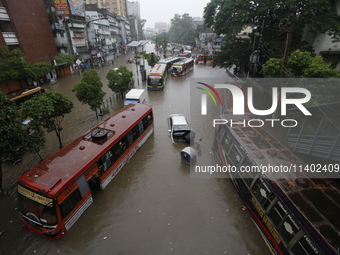 People are going through a flooded street after heavy monsoon rainfall in Dhaka, Bangladesh, on July 12, 2024. (