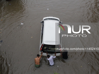 Men are pulling a vehicle through a flooded street after heavy monsoon rainfall in Dhaka, Bangladesh, on July 12, 2024. (