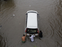 Men are pulling a vehicle through a flooded street after heavy monsoon rainfall in Dhaka, Bangladesh, on July 12, 2024. (