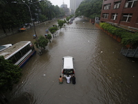 Men are pulling a vehicle through a flooded street after heavy monsoon rainfall in Dhaka, Bangladesh, on July 12, 2024. (