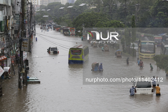 People are going through a flooded street after heavy monsoon rainfall in Dhaka, Bangladesh, on July 12, 2024. 