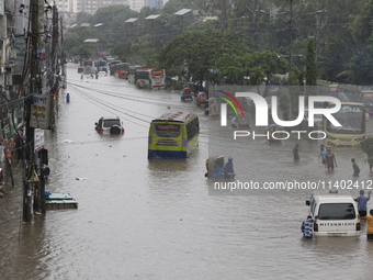 People are going through a flooded street after heavy monsoon rainfall in Dhaka, Bangladesh, on July 12, 2024. (