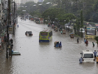 People are going through a flooded street after heavy monsoon rainfall in Dhaka, Bangladesh, on July 12, 2024. (