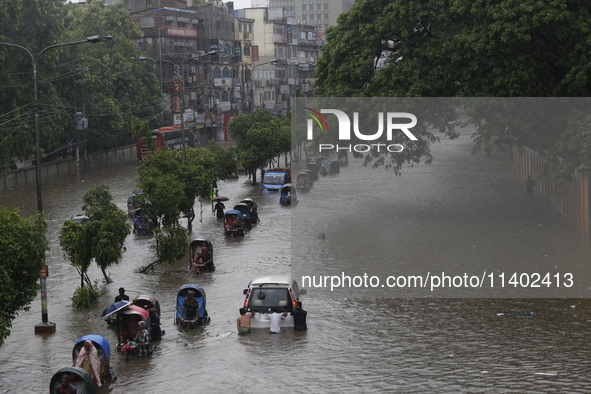 People are going through a flooded street after heavy monsoon rainfall in Dhaka, Bangladesh, on July 12, 2024. 