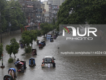 People are going through a flooded street after heavy monsoon rainfall in Dhaka, Bangladesh, on July 12, 2024. (