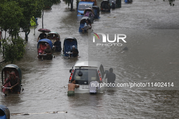 Men are pulling a vehicle through a flooded street after heavy monsoon rainfall in Dhaka, Bangladesh, on July 12, 2024. 