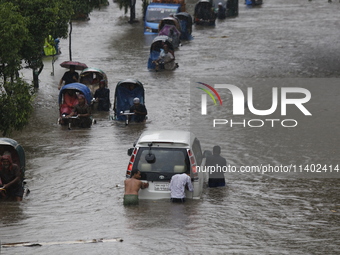 Men are pulling a vehicle through a flooded street after heavy monsoon rainfall in Dhaka, Bangladesh, on July 12, 2024. (