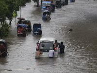 Men are pulling a vehicle through a flooded street after heavy monsoon rainfall in Dhaka, Bangladesh, on July 12, 2024. (