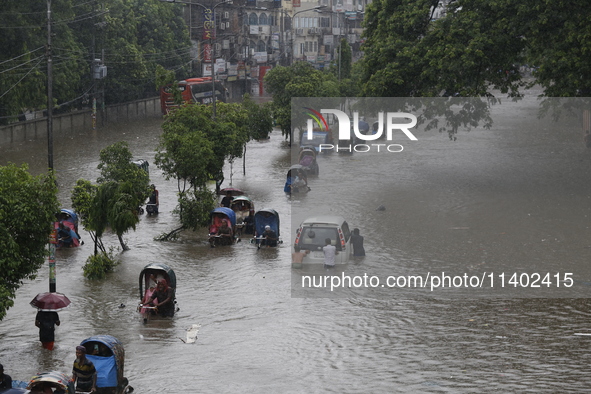 People are going through a flooded street after heavy monsoon rainfall in Dhaka, Bangladesh, on July 12, 2024. 