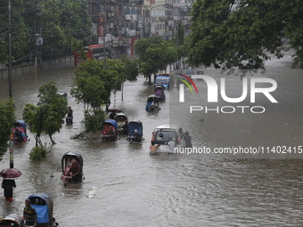 People are going through a flooded street after heavy monsoon rainfall in Dhaka, Bangladesh, on July 12, 2024. (