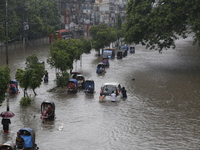 People are going through a flooded street after heavy monsoon rainfall in Dhaka, Bangladesh, on July 12, 2024. (