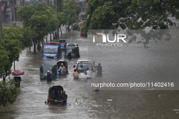 People are going through a flooded street after heavy monsoon rainfall in Dhaka, Bangladesh, on July 12, 2024. 