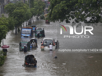 People are going through a flooded street after heavy monsoon rainfall in Dhaka, Bangladesh, on July 12, 2024. (