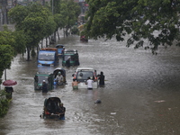 People are going through a flooded street after heavy monsoon rainfall in Dhaka, Bangladesh, on July 12, 2024. (