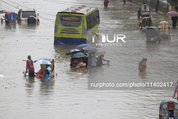 People are going through a flooded street after heavy monsoon rainfall in Dhaka, Bangladesh, on July 12, 2024. 