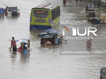 People are going through a flooded street after heavy monsoon rainfall in Dhaka, Bangladesh, on July 12, 2024. (