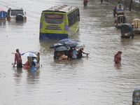 People are going through a flooded street after heavy monsoon rainfall in Dhaka, Bangladesh, on July 12, 2024. (