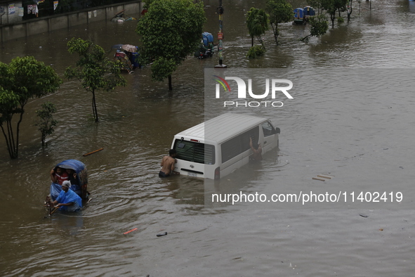 People are going through a flooded street after heavy monsoon rainfall in Dhaka, Bangladesh, on July 12, 2024. 