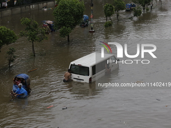 People are going through a flooded street after heavy monsoon rainfall in Dhaka, Bangladesh, on July 12, 2024. (