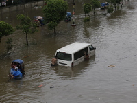 People are going through a flooded street after heavy monsoon rainfall in Dhaka, Bangladesh, on July 12, 2024. (