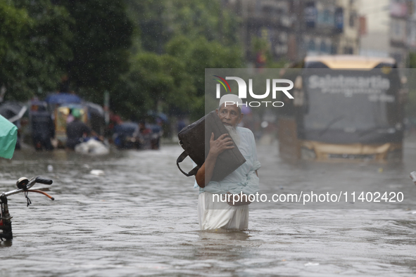 A man is going through a flooded street after heavy monsoon rainfall in Dhaka, Bangladesh, on July 12, 2024. 