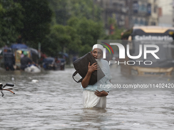 A man is going through a flooded street after heavy monsoon rainfall in Dhaka, Bangladesh, on July 12, 2024. (