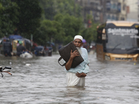 A man is going through a flooded street after heavy monsoon rainfall in Dhaka, Bangladesh, on July 12, 2024. (