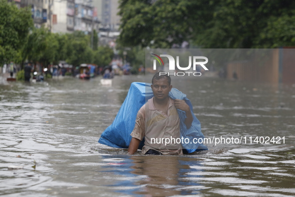 A man is going through a flooded street after heavy monsoon rainfall in Dhaka, Bangladesh, on July 12, 2024. 